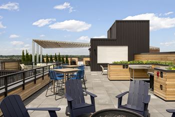A patio with blue chairs and a table is surrounded by buildings.